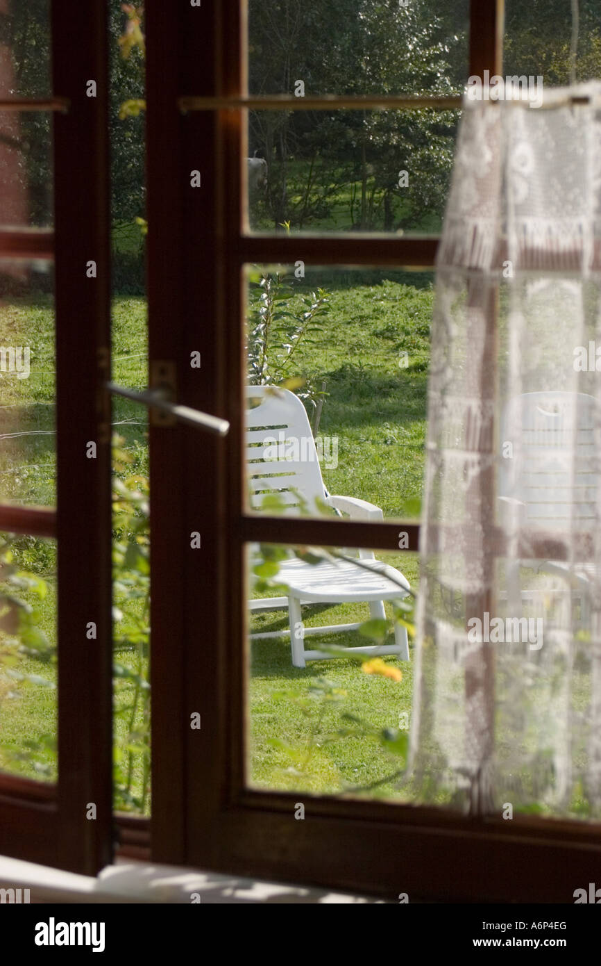 View into garden through slightly opened windows with traditional timber frames France Stock Photo