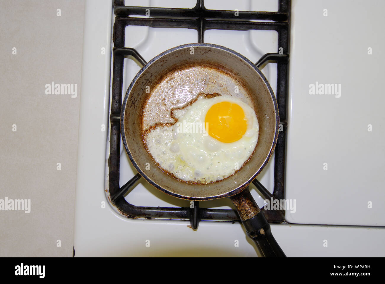 one egg frying in small frying pan on a stove stock photo
