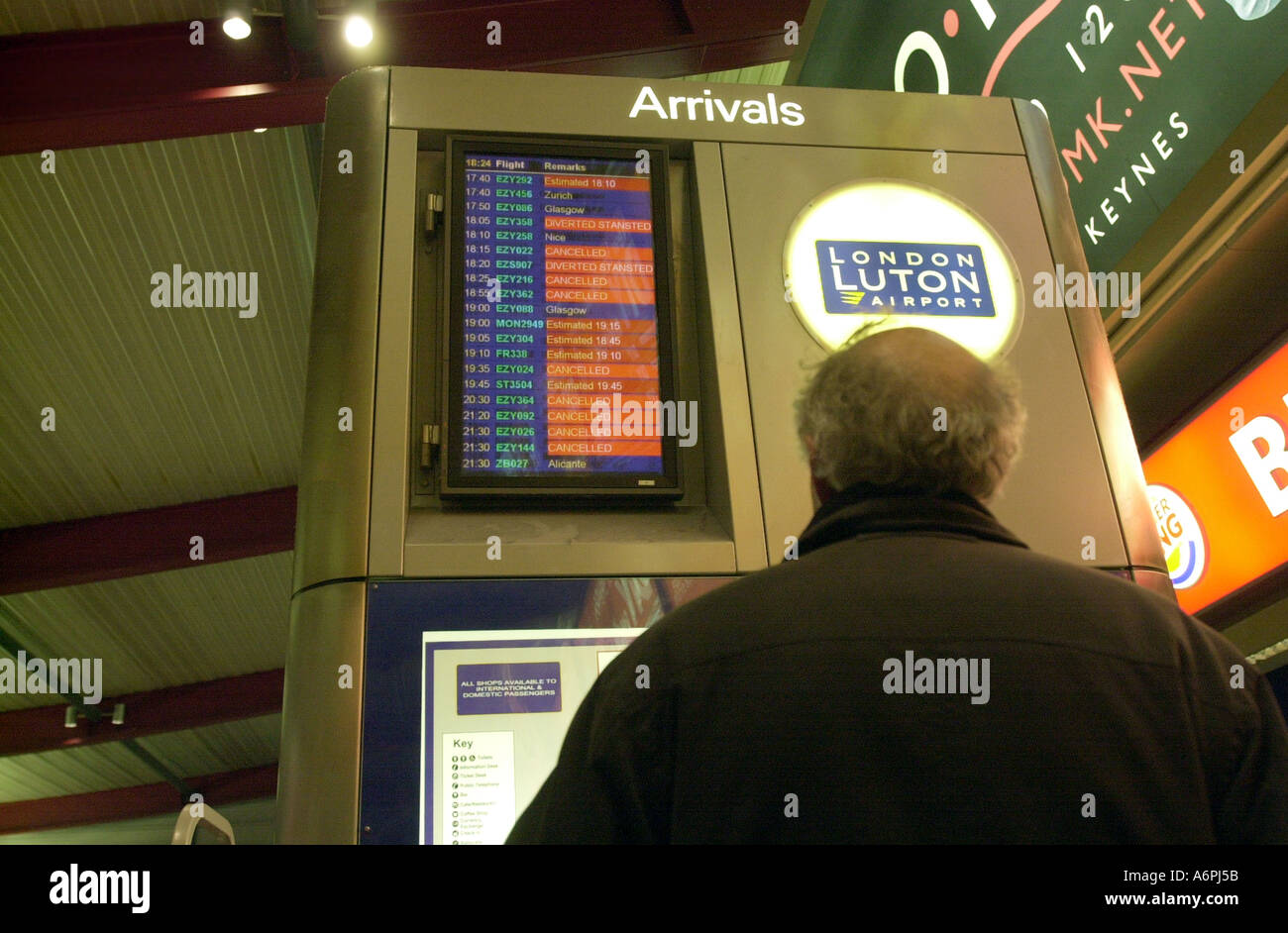 Passenger checks the arrivals board at Luton airport UK Stock Photo