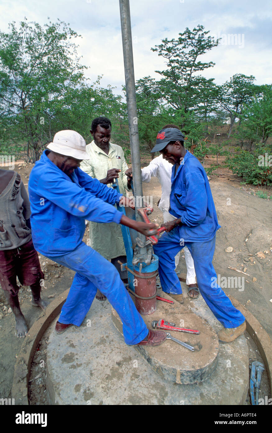 Trained mechanics fitting a bush pump head. Zimbabwe Stock Photo