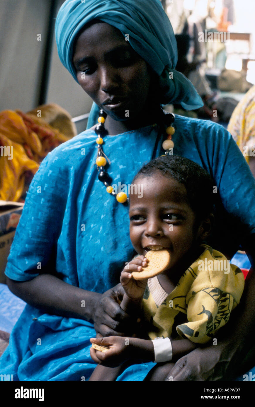 Woman with malnourished Somali child eating a high energy biscuit at a feeding centre in Ethiopia Stock Photo