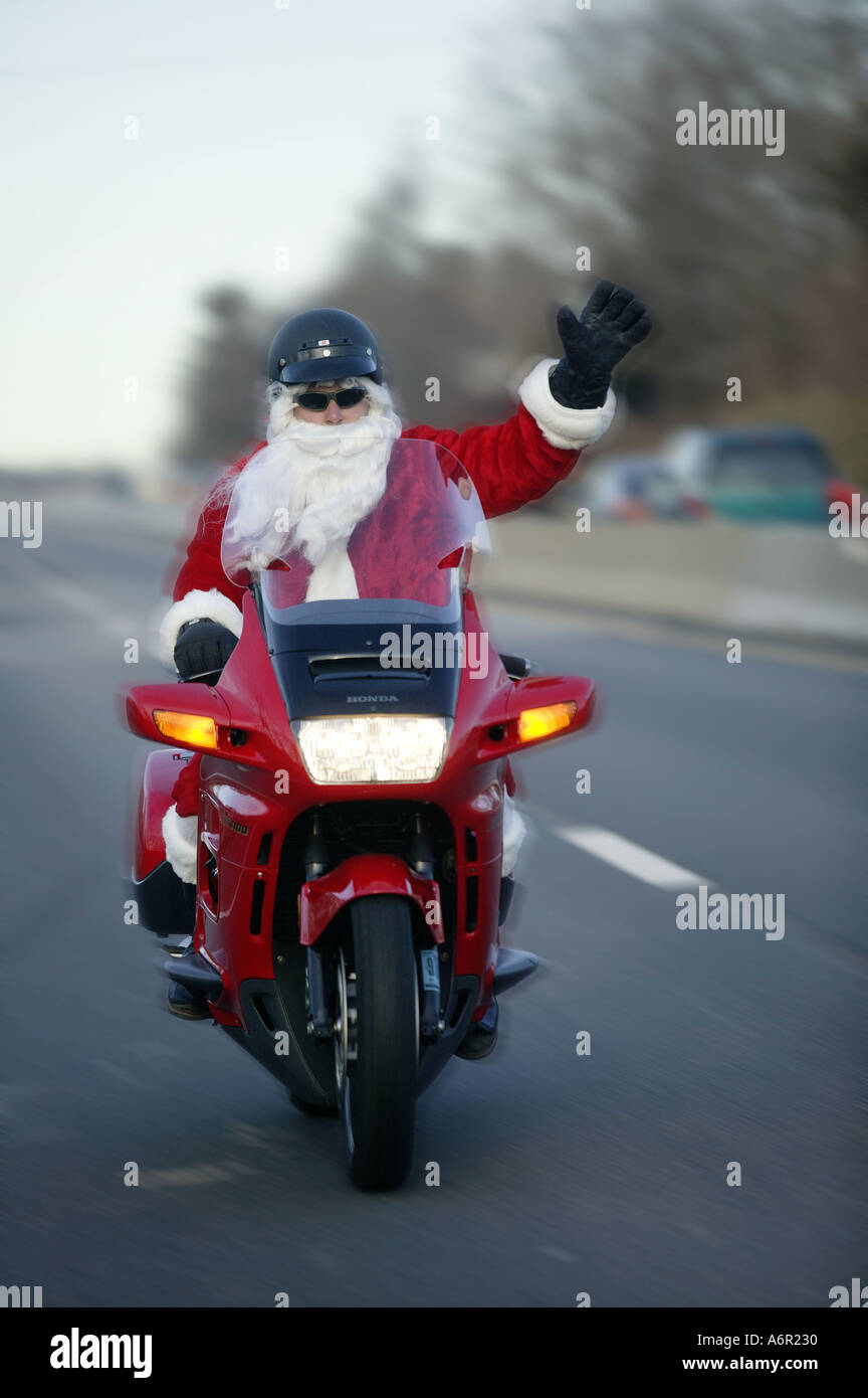 A motorcyclist rides his bright red motorcycle down the highway wearing a Santa  Claus suit waving to other motorists at Christmas time Stock Photo - Alamy