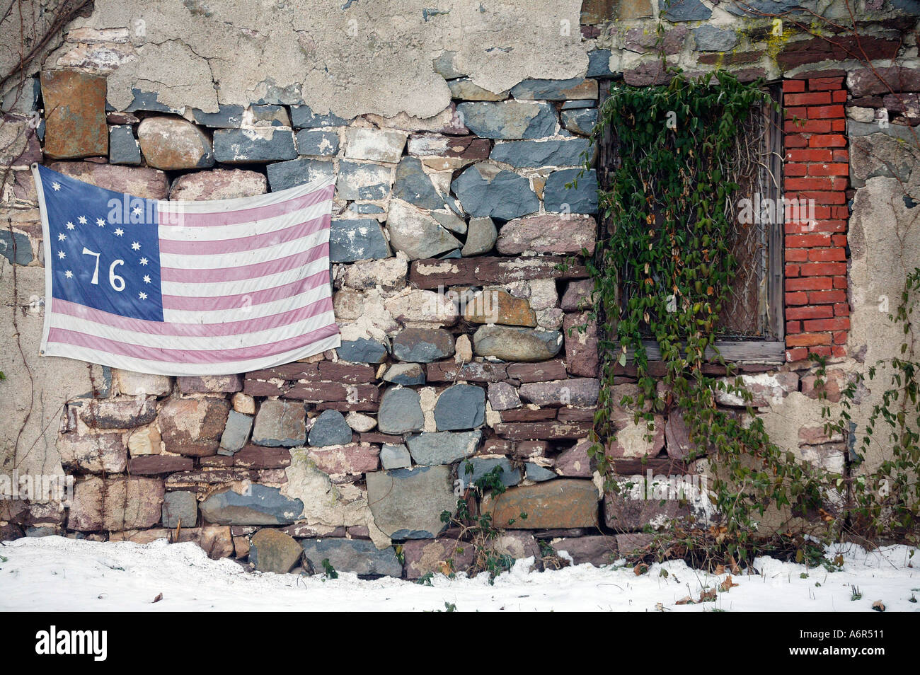 A 1776 bi centennial United States flag hangs from a rustic rock wall ...