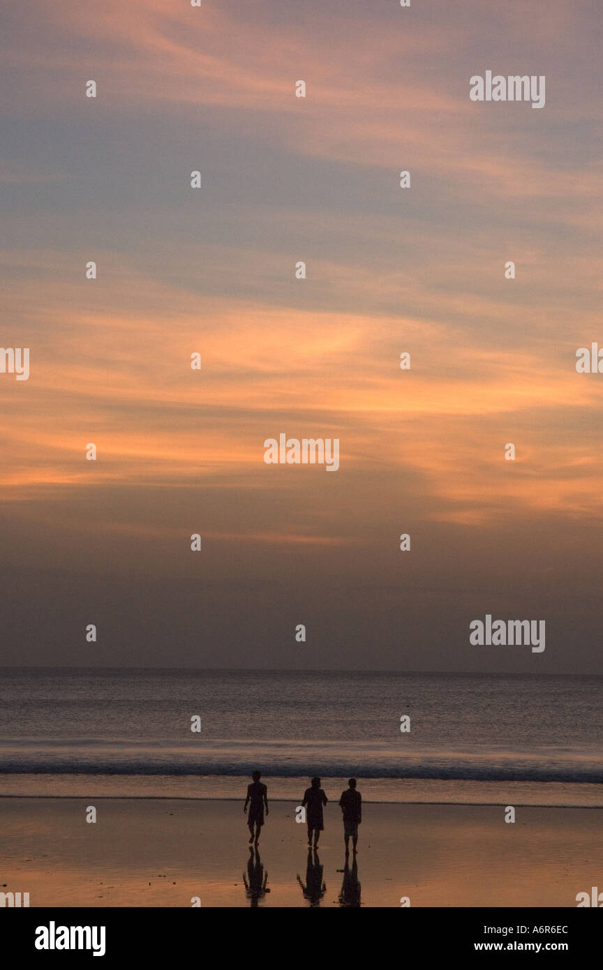 Three People Walking On Beach At Sunset On Kuta Beach Bali Indonesia