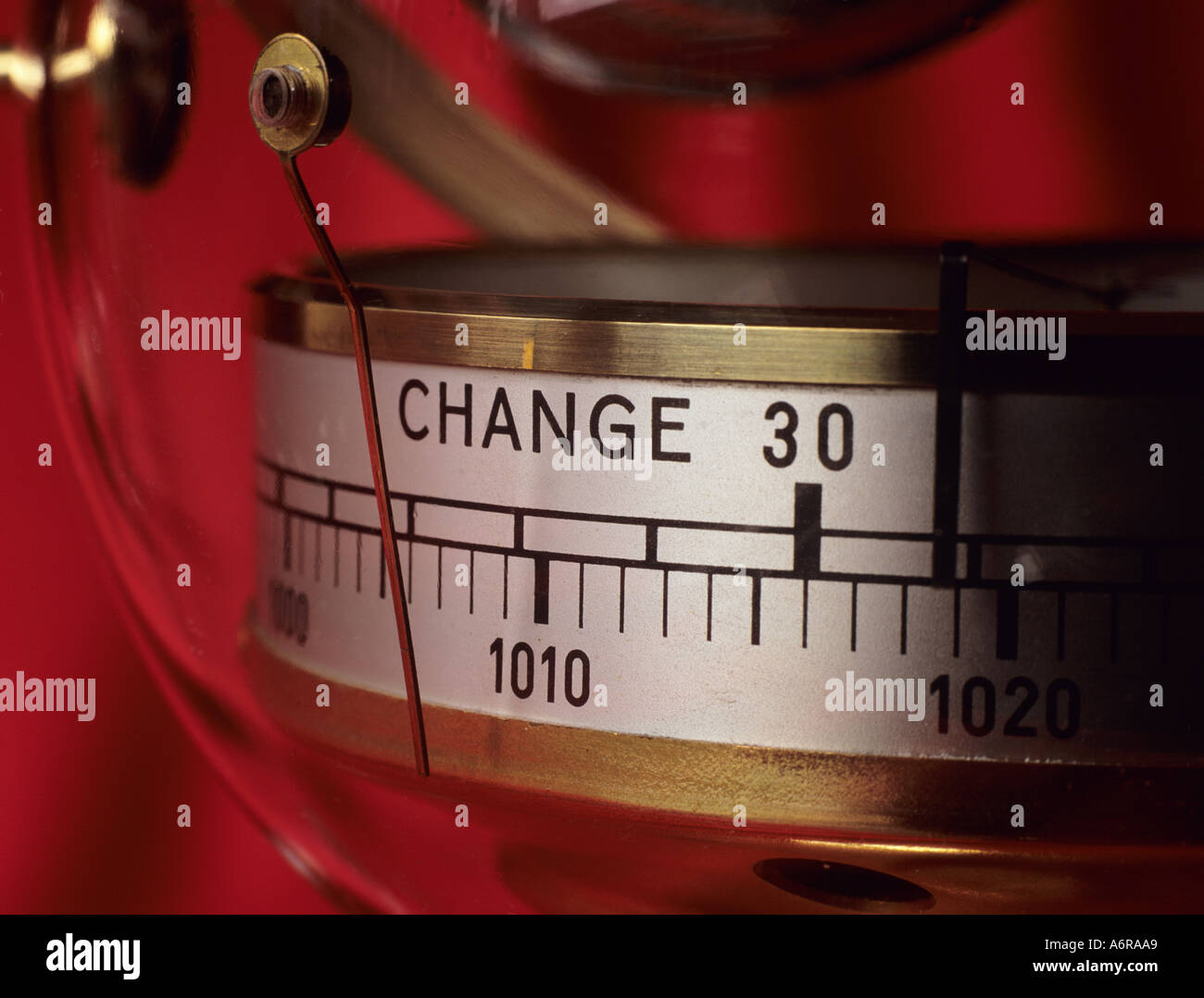 Aneroid barometer needle pointing to indicate change against a red background. UK Britain Stock Photo