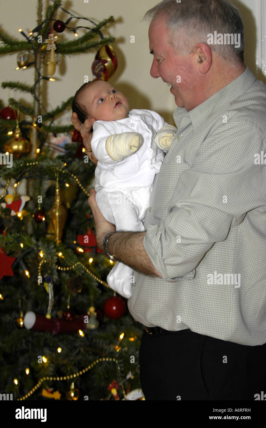 grandfather grandad holding baby grandaughter vertical colour color christmas tree Stock Photo