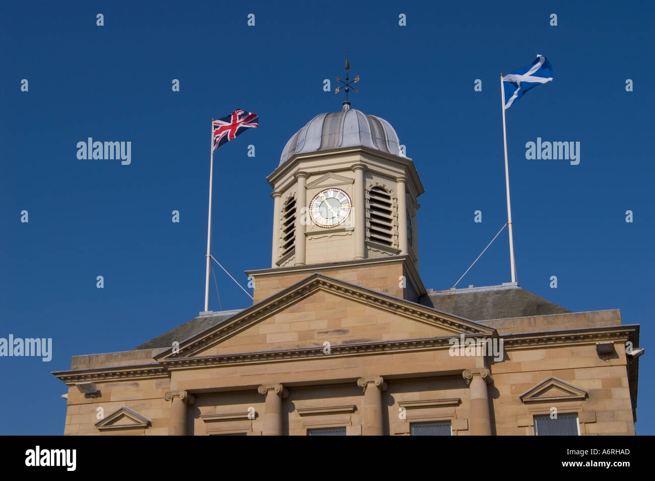 Union Jack and Scottish Saltire flags flying side by side above the Town Hall of Kelso in the Scottish Borders UK Stock Photo