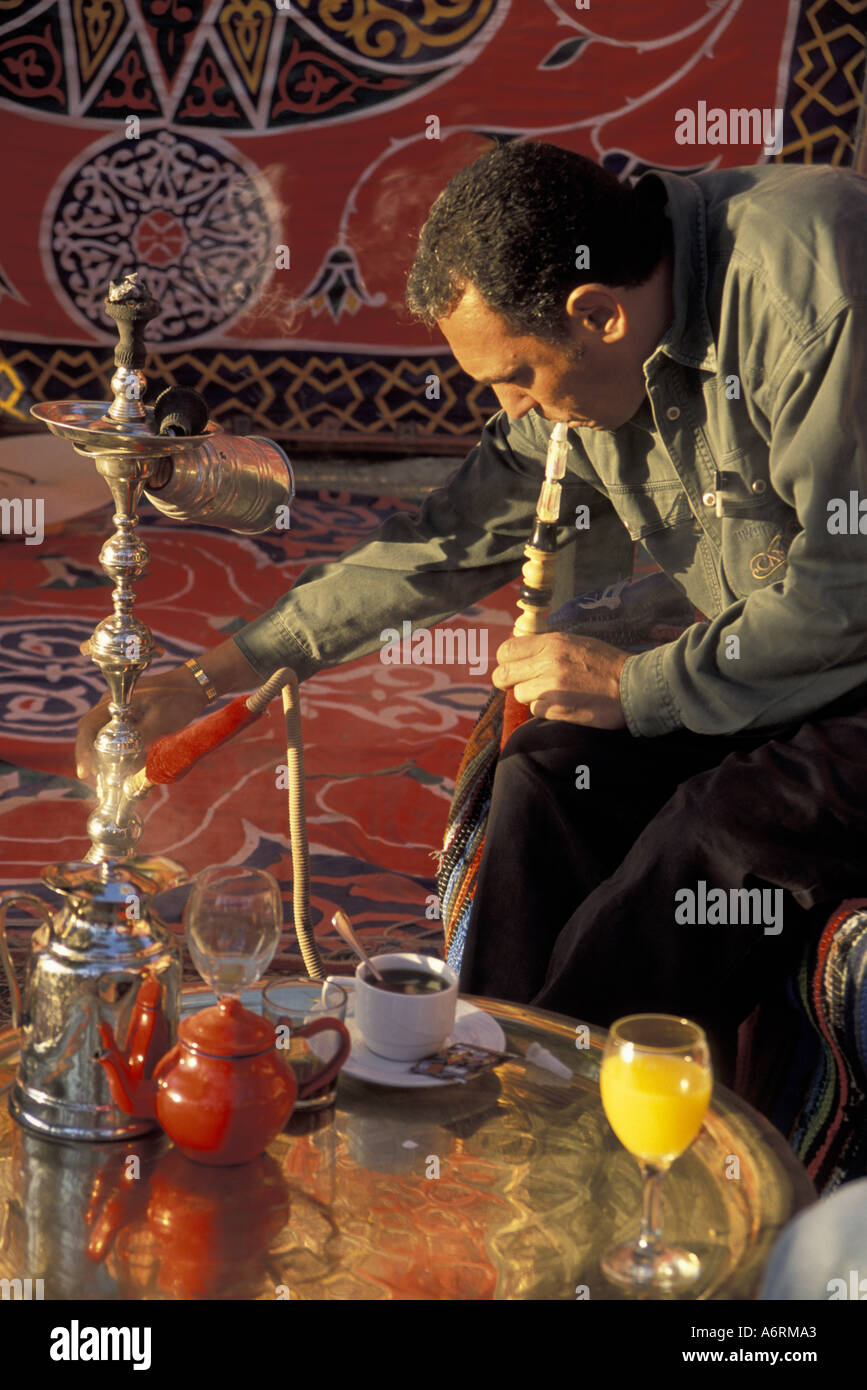 Africa, Egypt, Luxor, Bedouin Camp. Egyptian man smoking a water pipe in a Bedouin tented camp
