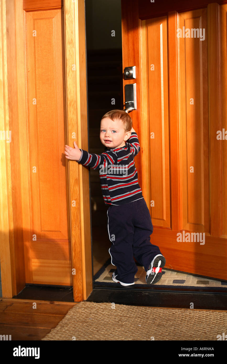 18 Month Old Boy Walking In Front Door Of House Stock Photo