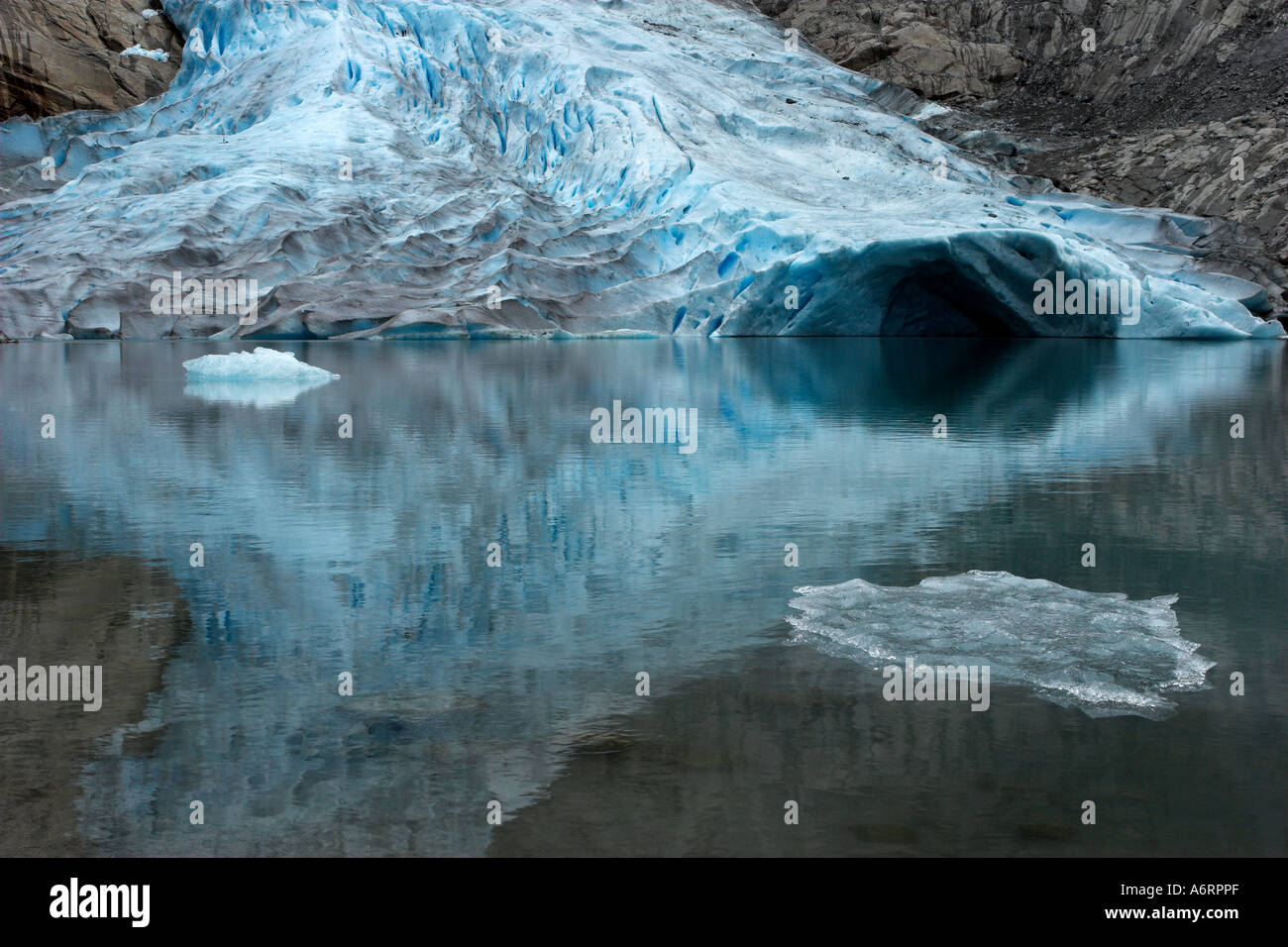 The mouth of the Briksdalbreen glacier in Norway is perfectly reflected in the mirror like glacial pool. Stock Photo