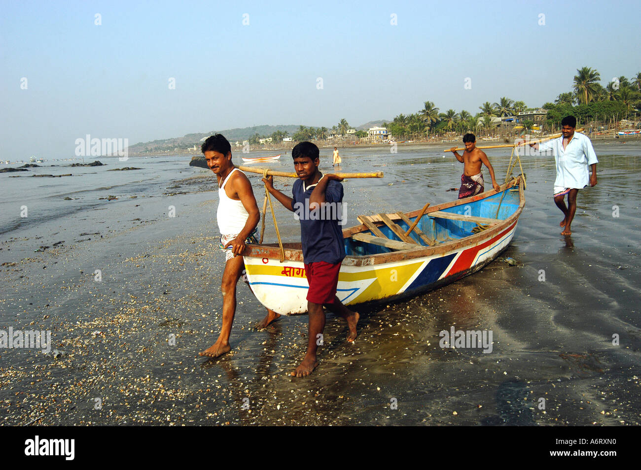 Four Indian Fishermen together lifting fishing boat out to sea for