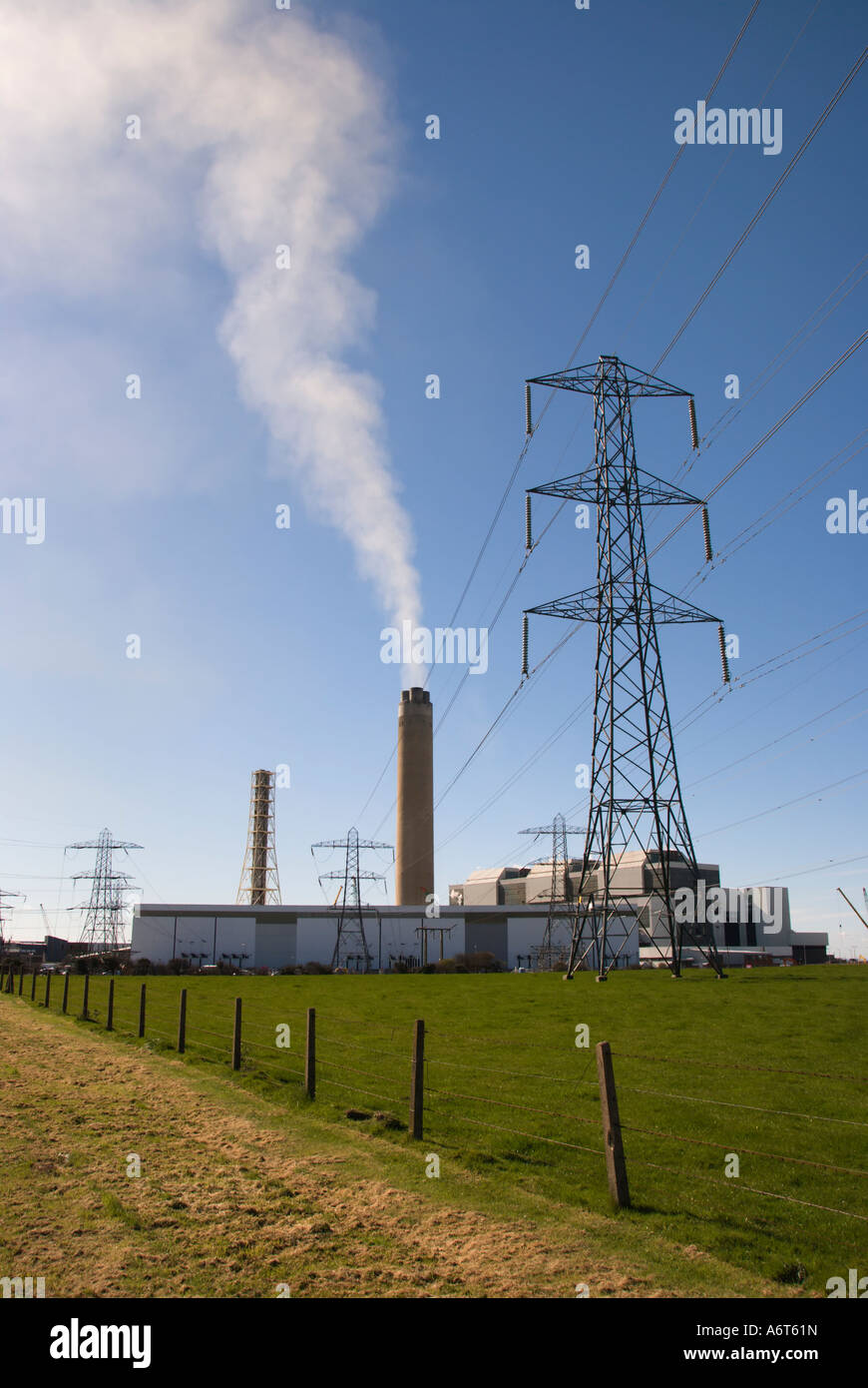A power station with smoking chimney stack. There is also  an electricity pylon. Aberthaw , South Wales. Stock Photo