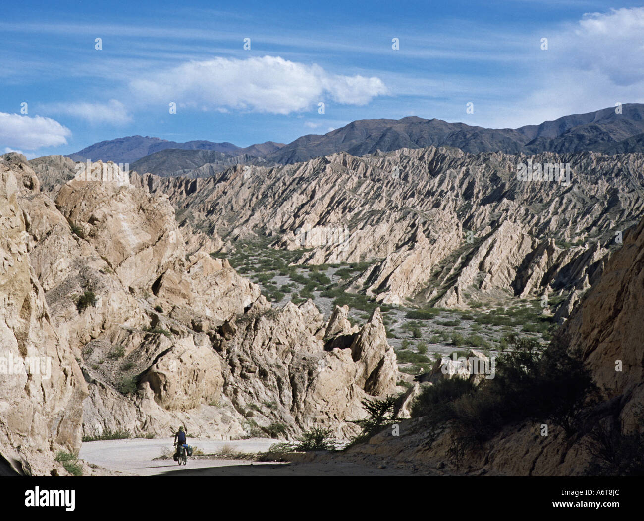 Single touring cyclist on rough road amidst strange rock formations in northern Argentina Stock Photo
