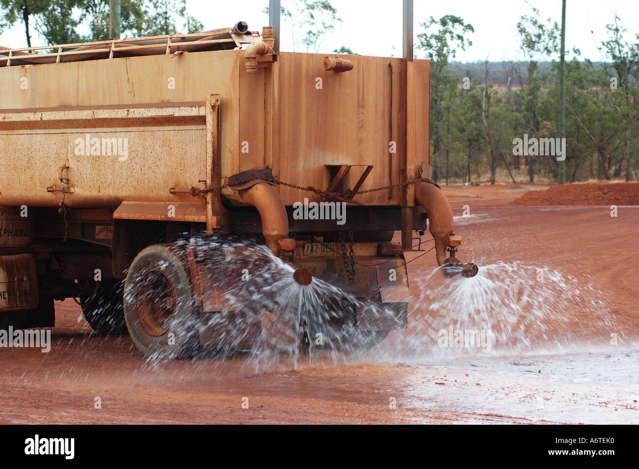 Water tanker suppresses red dust and earth at mine site Stock Photo - Alamy