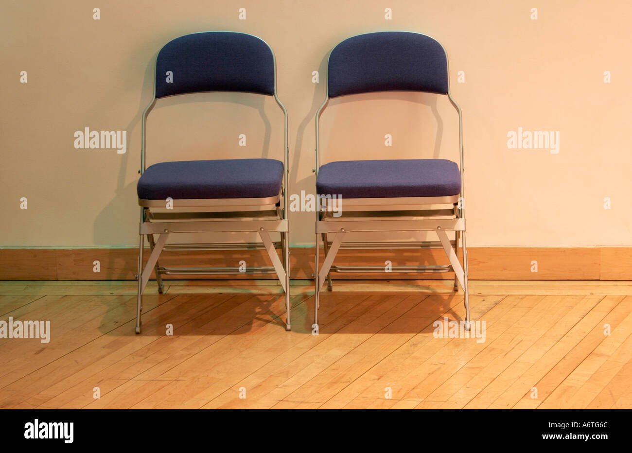 Two Chairs side by side against a wall on a wooden floor Stock Photo Alamy