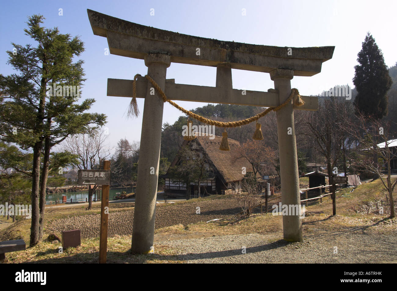 Japan Central Honshu Hida District Takayama Hida No Sato Hida Folk Village backlit Shinto torii with traditional house in bkgd Stock Photo