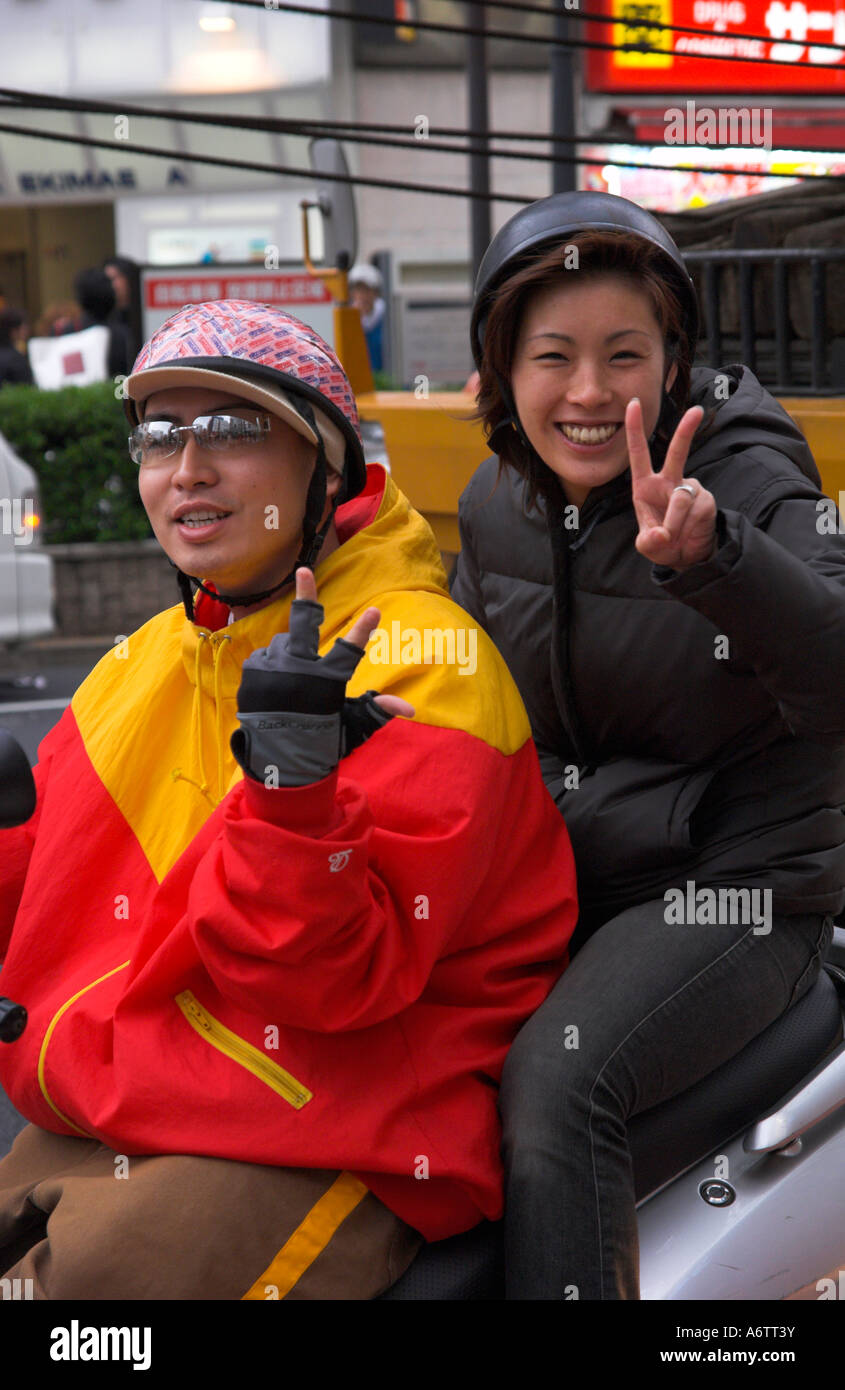 Japan Central Honshu Tokyo shibuya street scene young couple riding a scooter and making the V sign to the camera Stock Photo