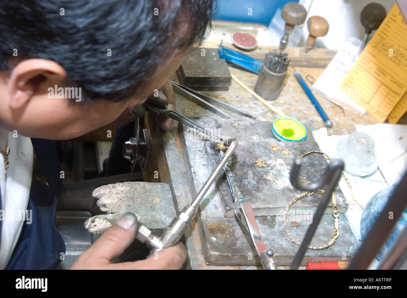 jeweler craftsman working at his bench with a torch and tweezers