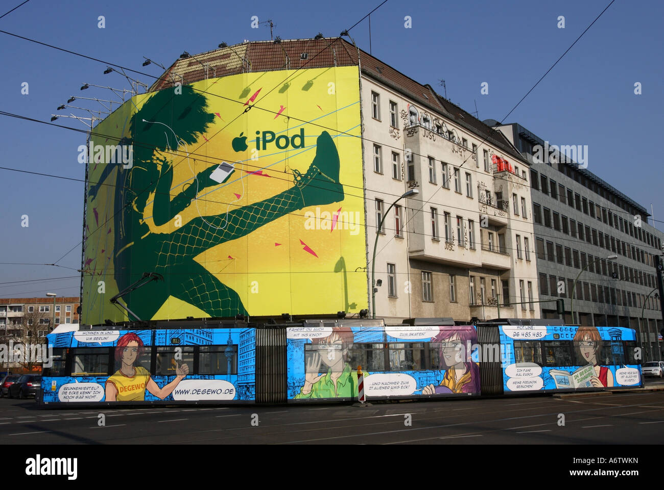 Colorful comic tram in front of huge advertisement banner that promotes apples ipod on abuilding facade in Berlin, Germany, Eur Stock Photo
