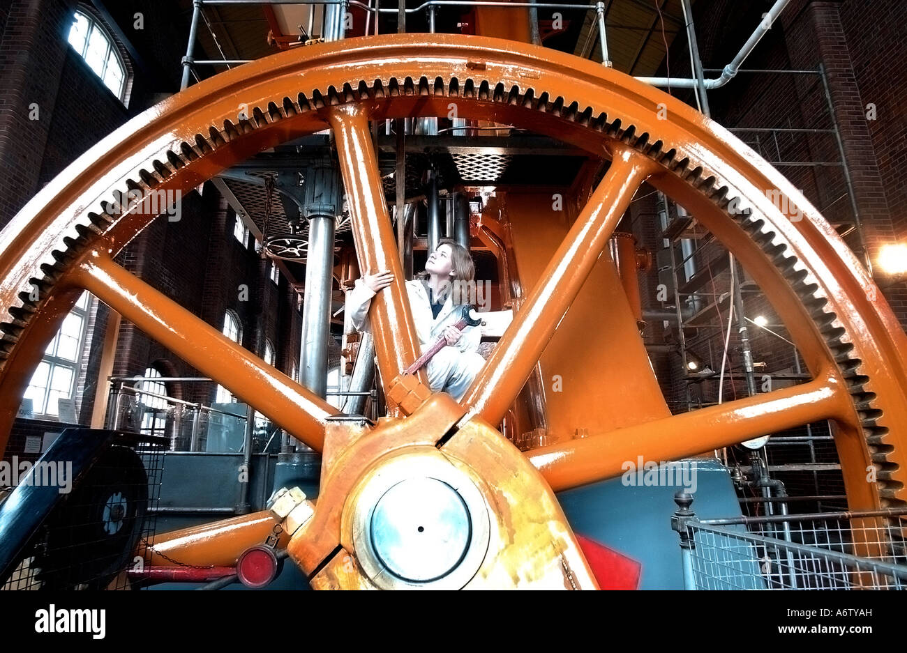 Southern Water apprentice Caroline Gardiner examines the flywheel of a 99 year old Tangye 420hp steam driven pumping engine. Stock Photo