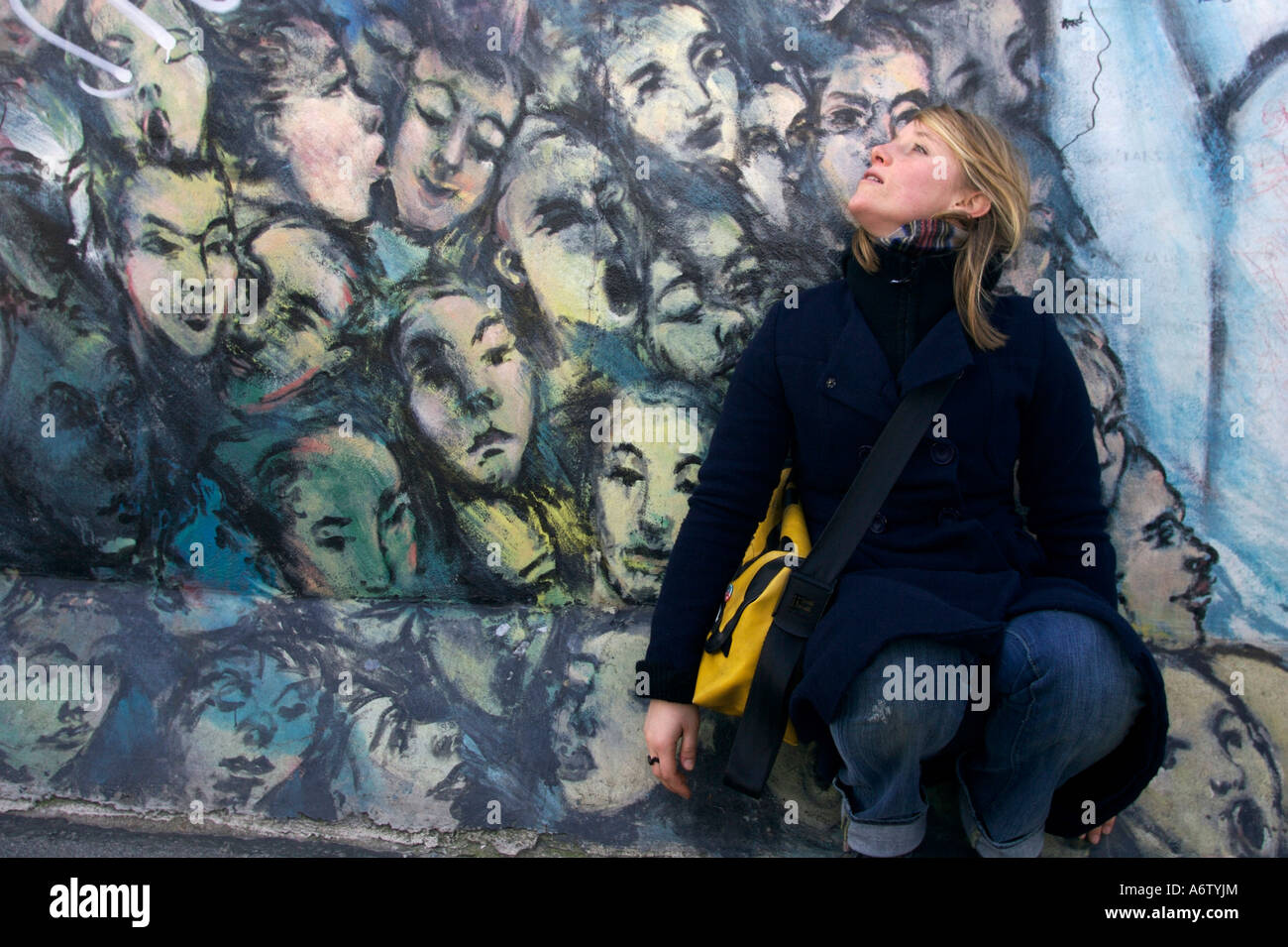 Young woman in front of Graffiti on the Berlin Wall, East Side Gallery, Berlin, Germany Stock Photo