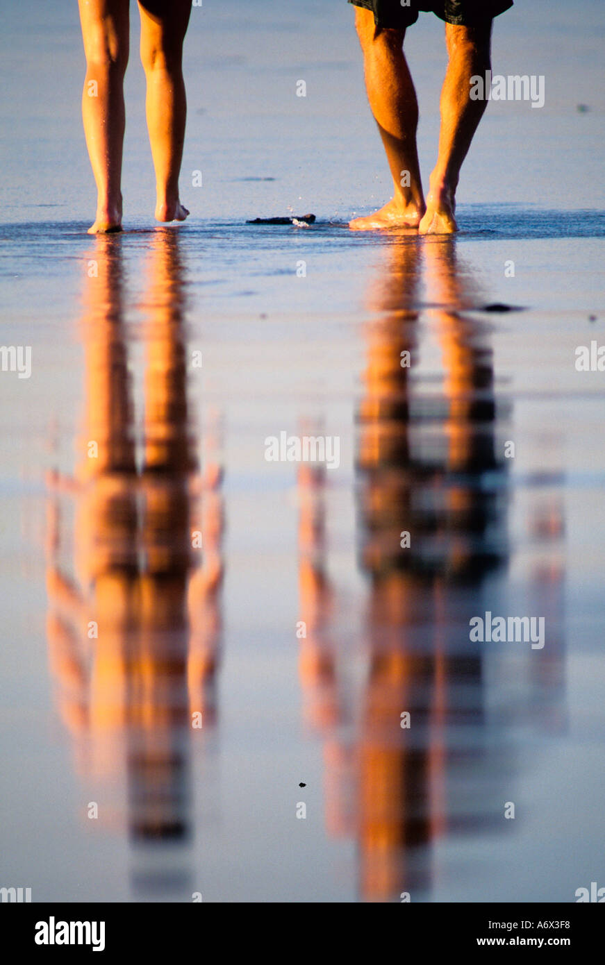 A couple on the beach reflection in the wet sand Stock Photo