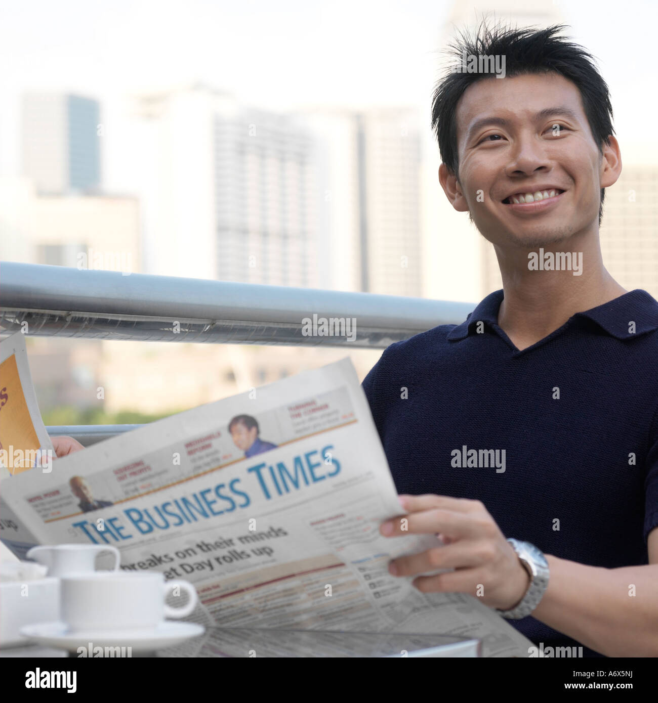 Young man reading newspaper at an outdoor cafe Stock Photo - Alamy
