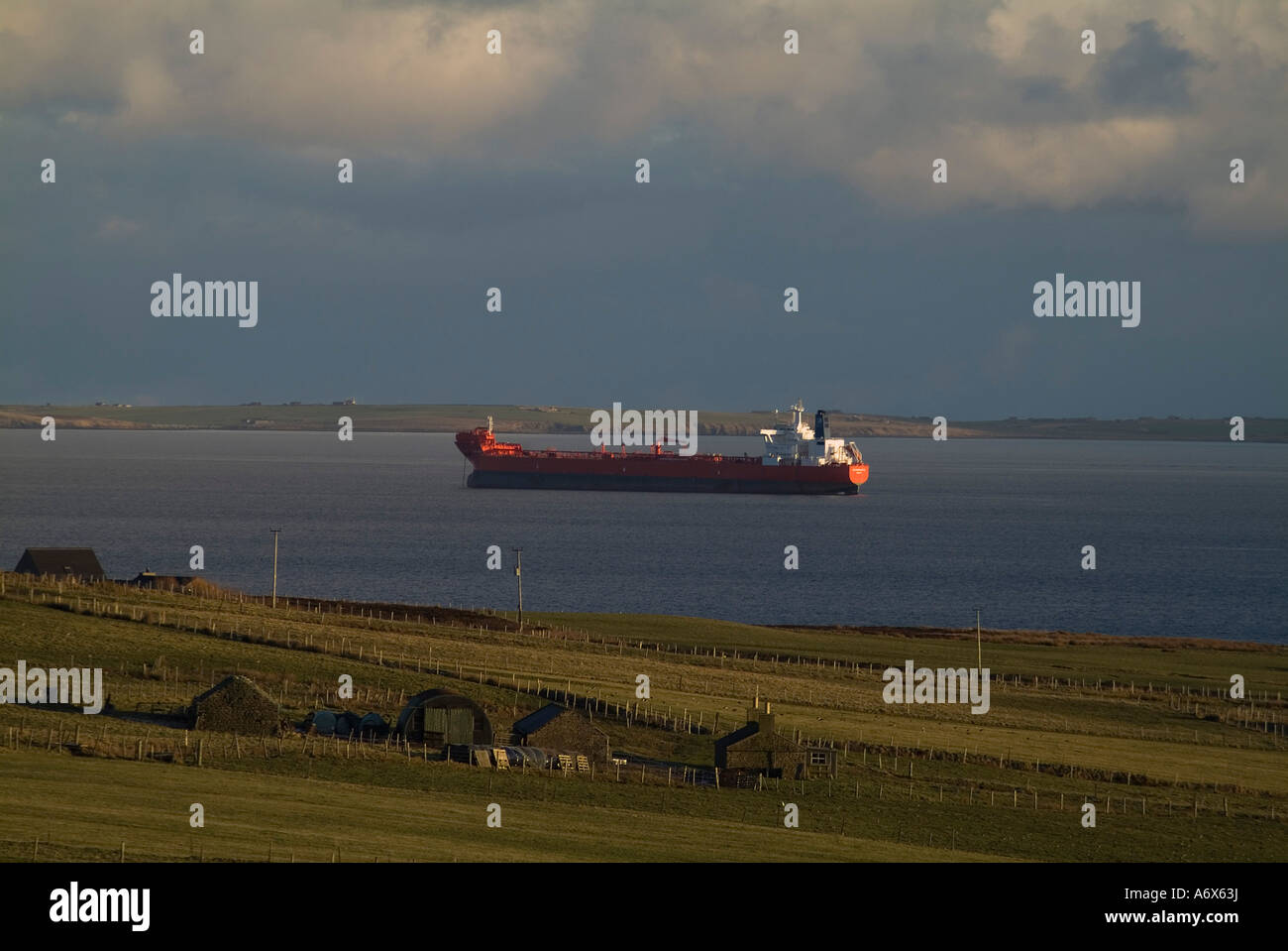 dh Oil tanker SHIPPING UK Oiltanker anchorage awaiting oil transfer in Scapa Flow and cottage Stock Photo