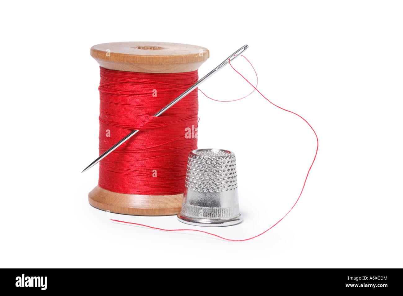 Thimble, needle and spool of thread cut out on white background Stock Photo