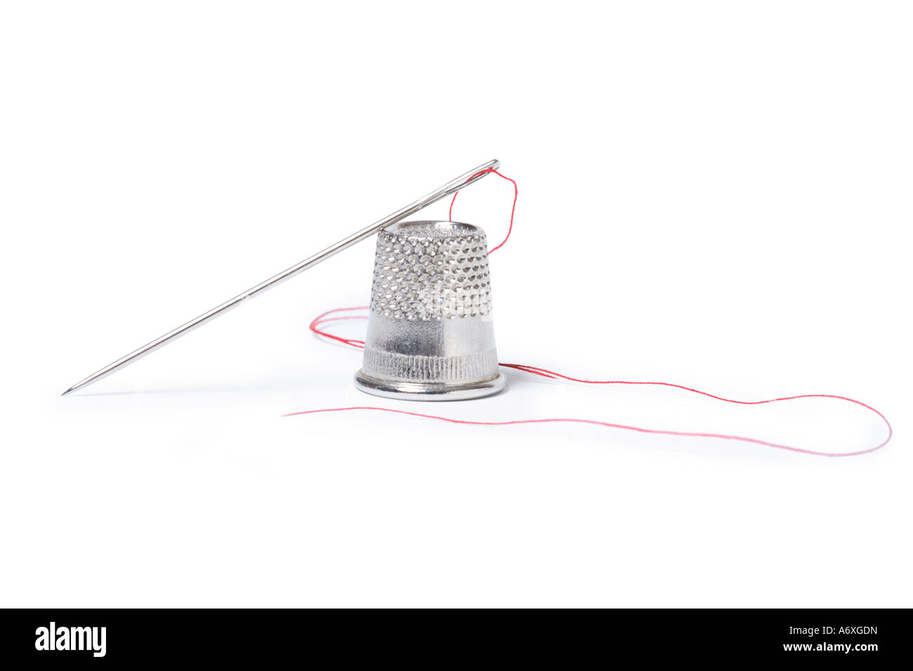 Thimble, needle and thread cut out on white background Stock Photo