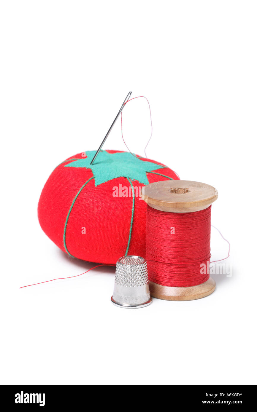 Pincushion, thimble and spool of thread cut out on white background Stock Photo