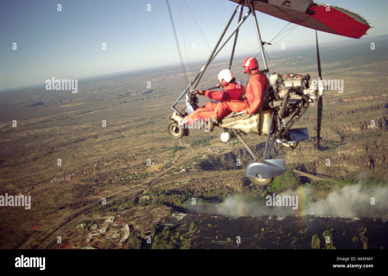 tandem tourist and pilot flying in a microlite approaching victoria falls mosi oa tunya zimbabwe and zambia africa Stock Photo