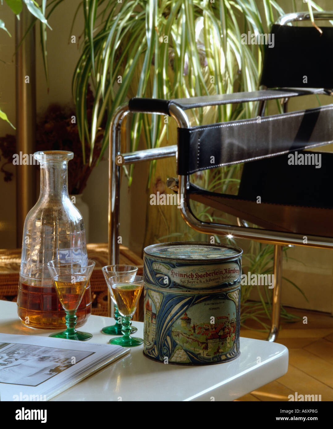 Close-up of glass decanter and two glasses of sherry on table with old tin in front of  Breuer 'Wassily' chair Stock Photo