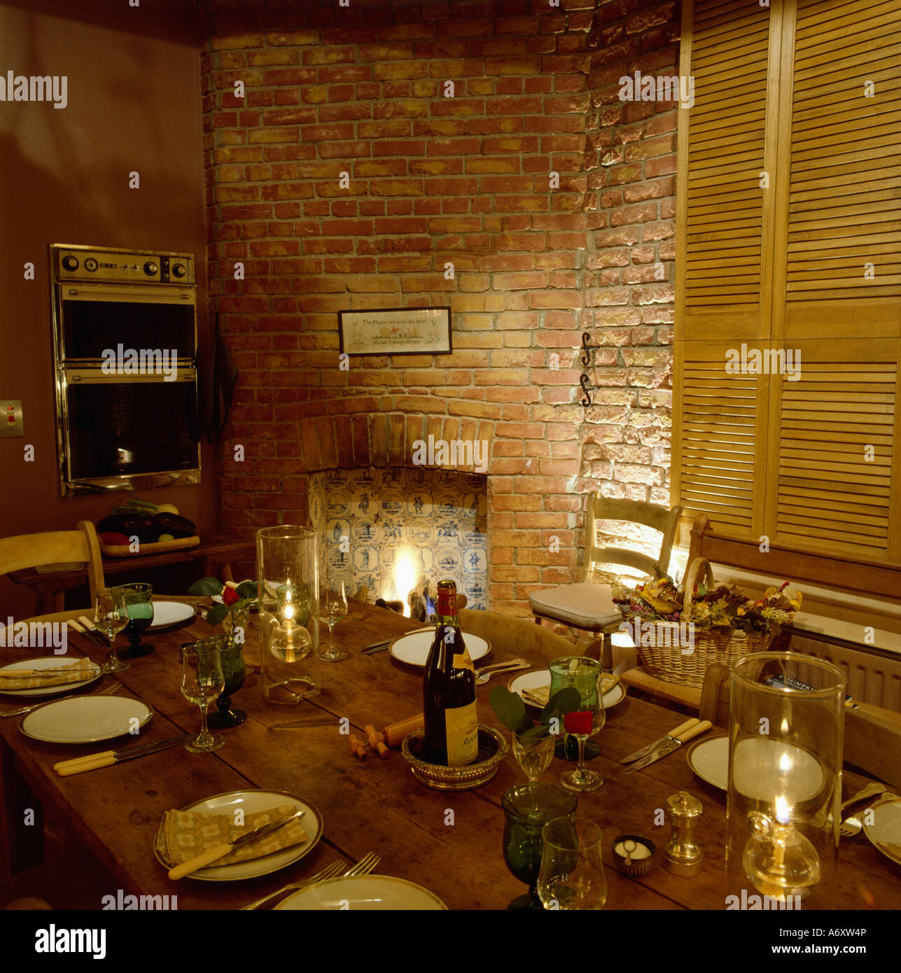 Dining table with place settings beside fireplace in brick wall Stock Photo