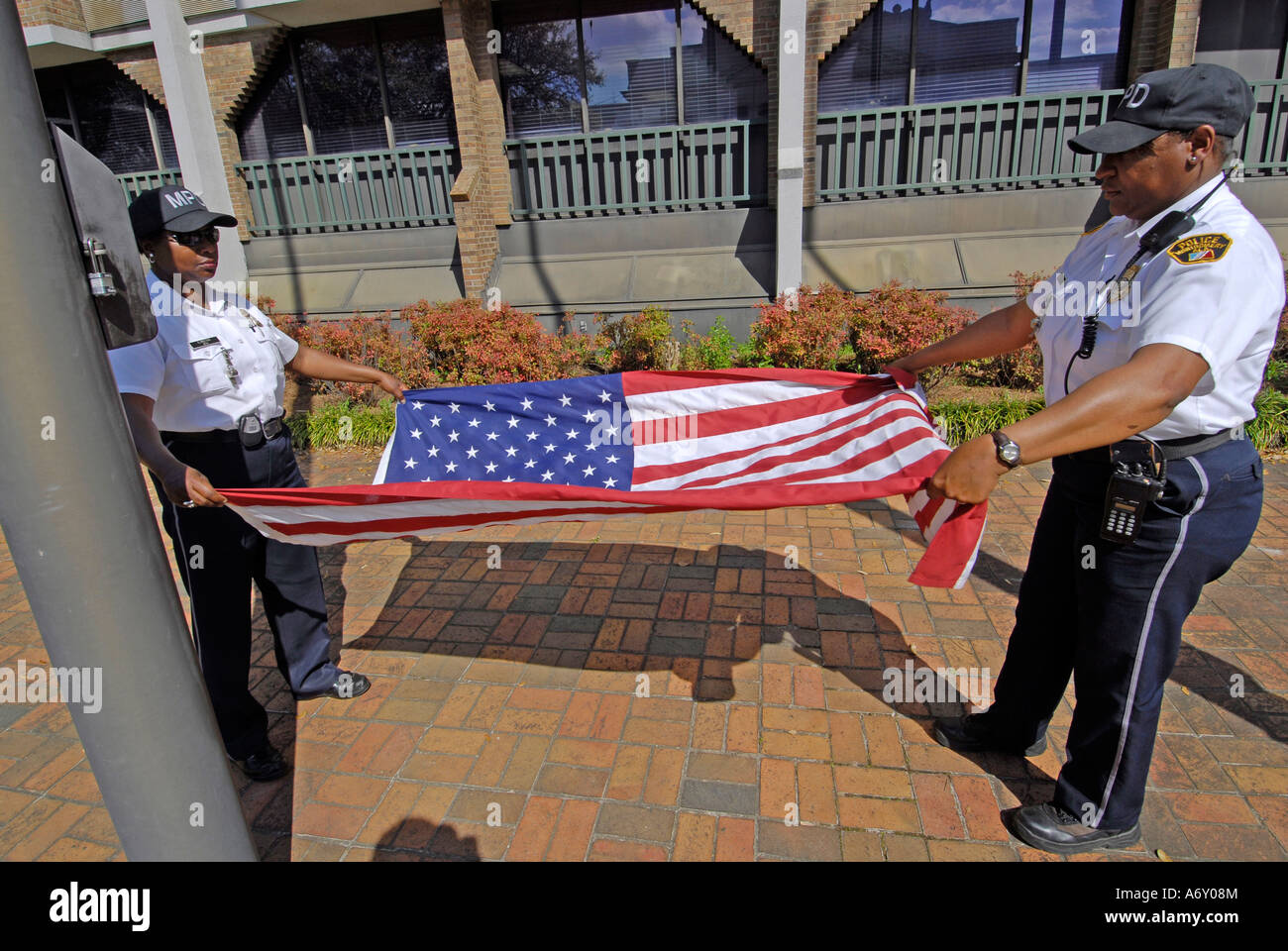 Black female police officers take the America flag down a fold it at