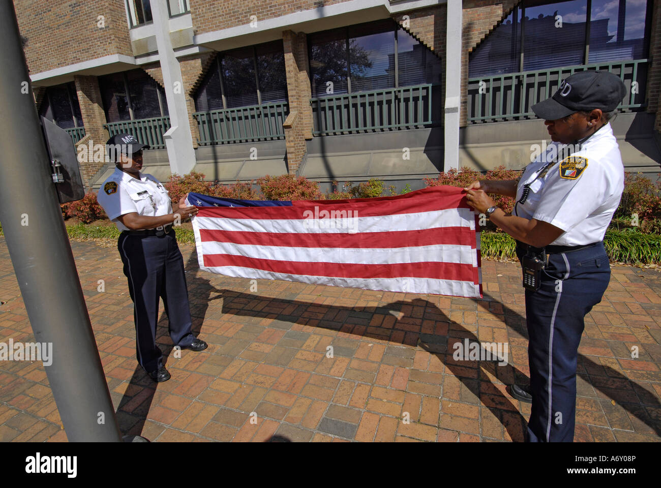 Black female police officers take the America flag down a fold it at