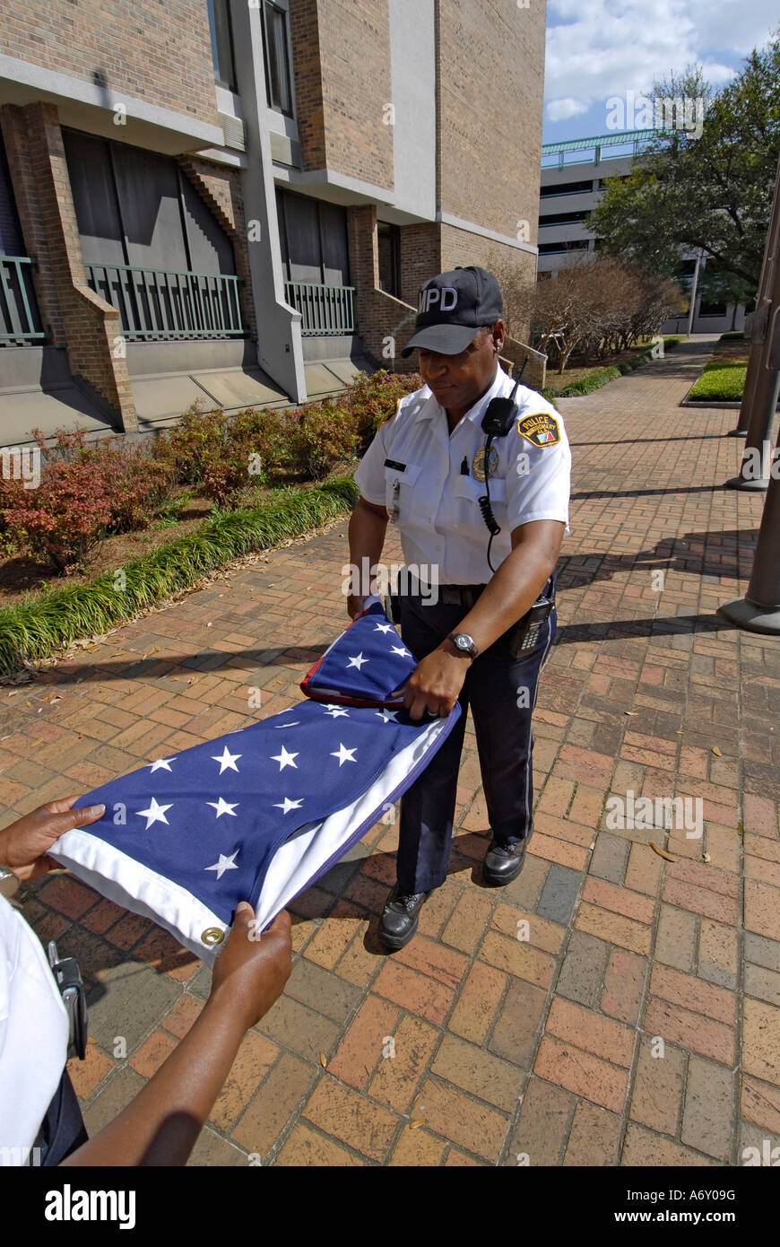 Black female police officers take the America flag down a fold it at the end of the day in Montgomery Alabama AL Stock Photo