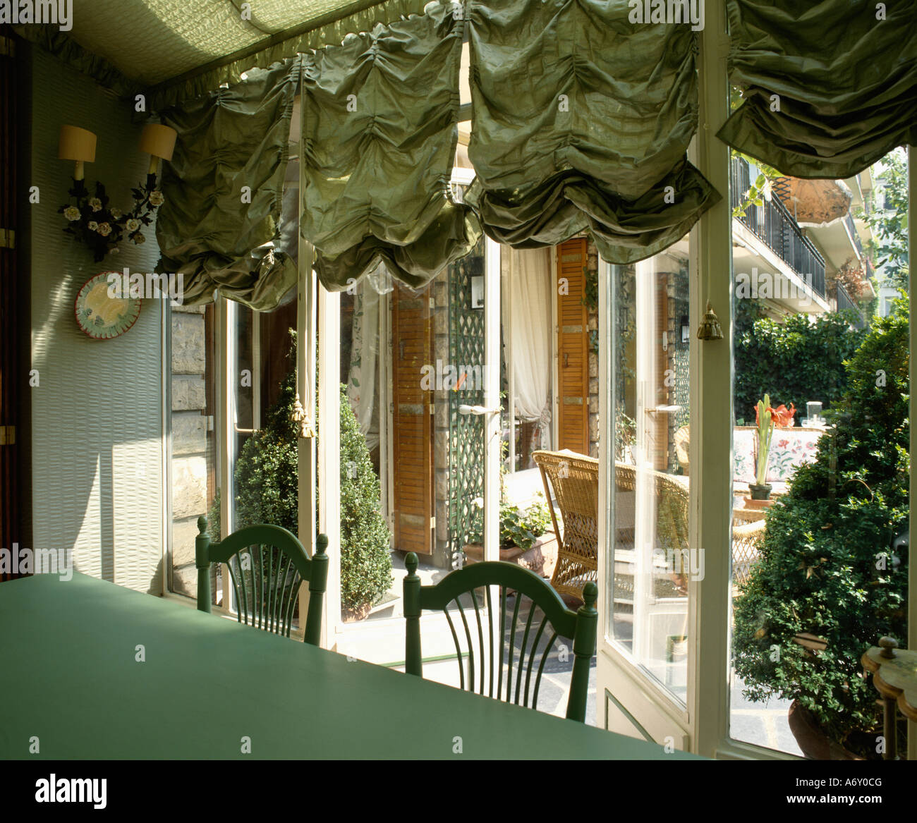 Green festoon blinds at windows in conservatory extension with view of  patio Stock Photo - Alamy