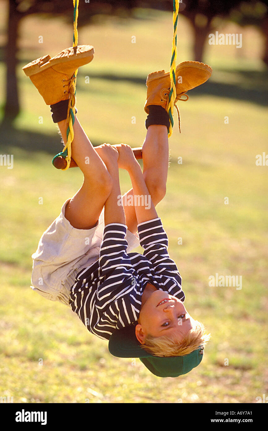 portrait of a boy hanging on swing in the park Stock Photo