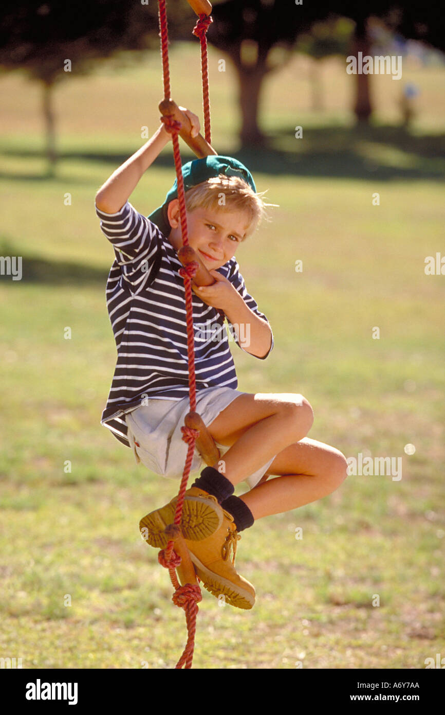 portrait of a boy sitting on a rope ladder in the park Stock Photo