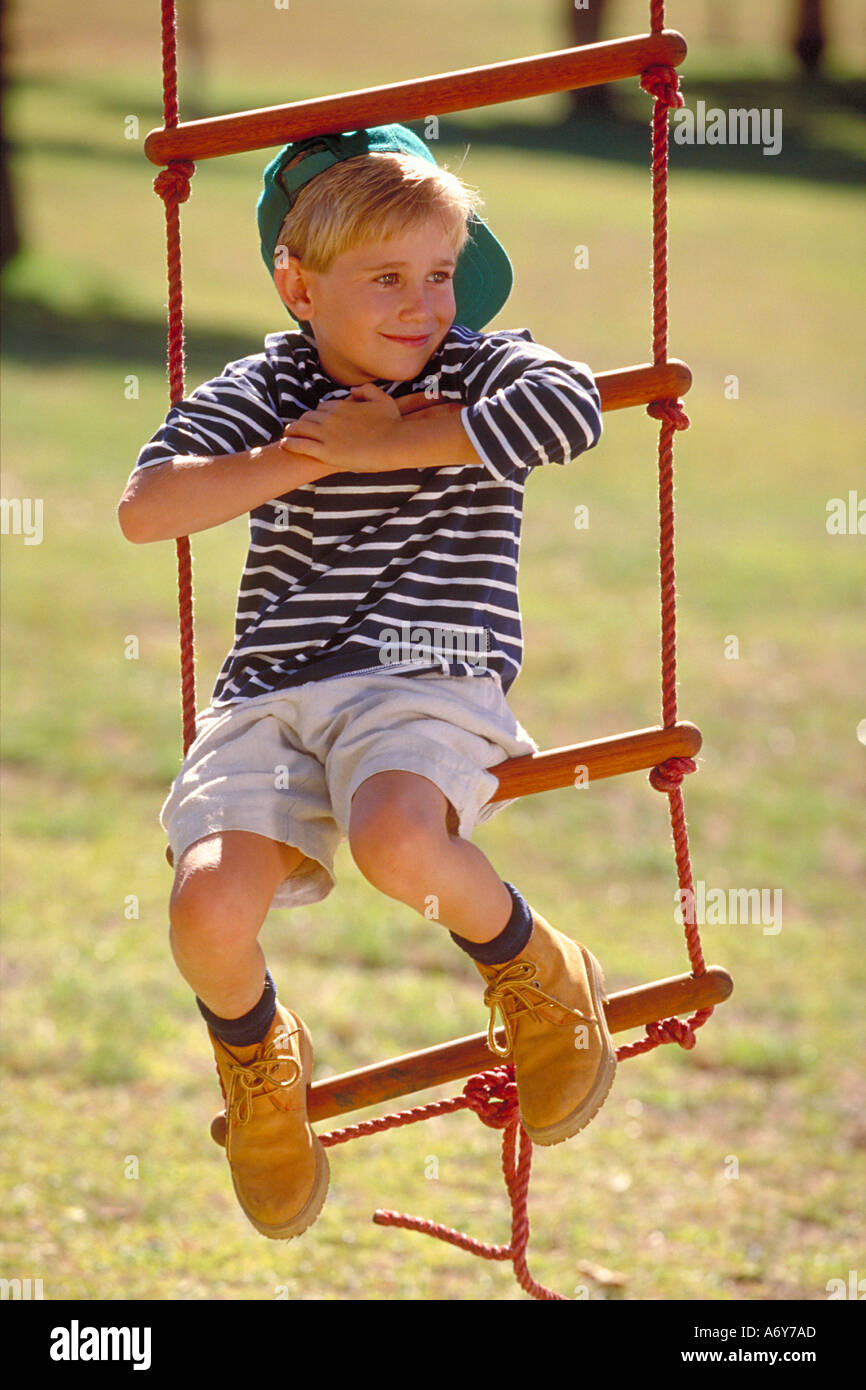 portrait of a boy sitting on a rope ladder in the park Stock Photo