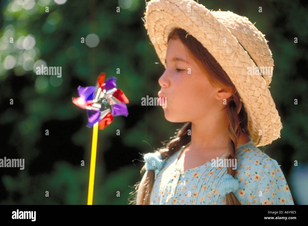 portrait of a girl with a straw hat blowing a wind wheel Stock Photo Alamy