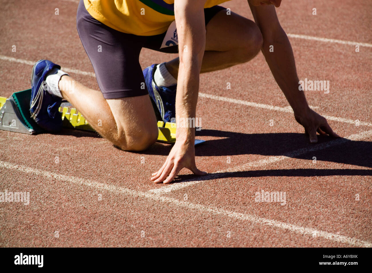 Male athlete in starting blocks on a running track Stock Photo - Alamy