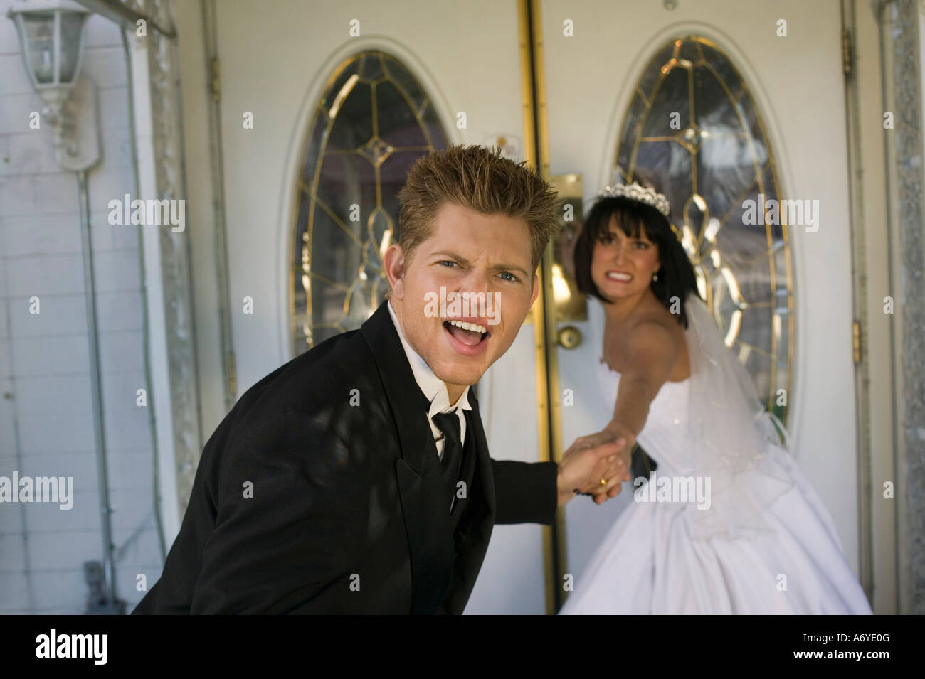 Bride dragging groom into a wedding chapel Stock Photo