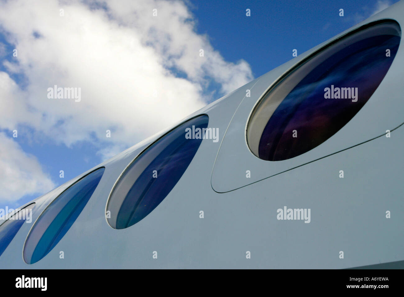 The windows of a jet against puffy white clouds and blue sky Stock ...