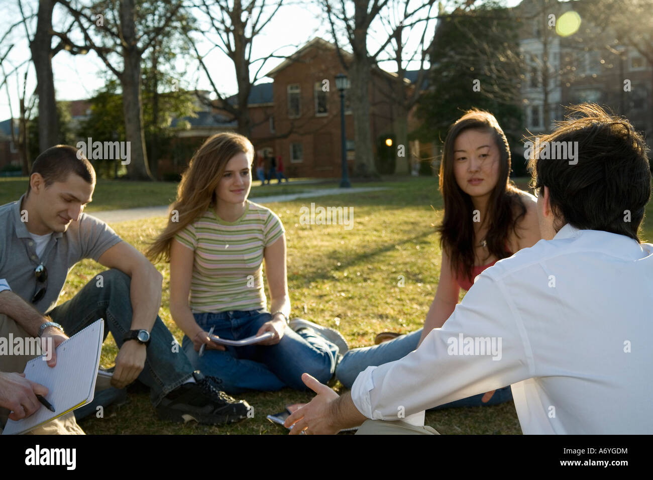 University students sitting on grass with lecturer Stock Photo - Alamy