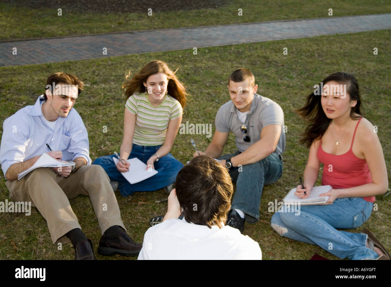 University students sitting on grass with lecturer Stock Photo - Alamy
