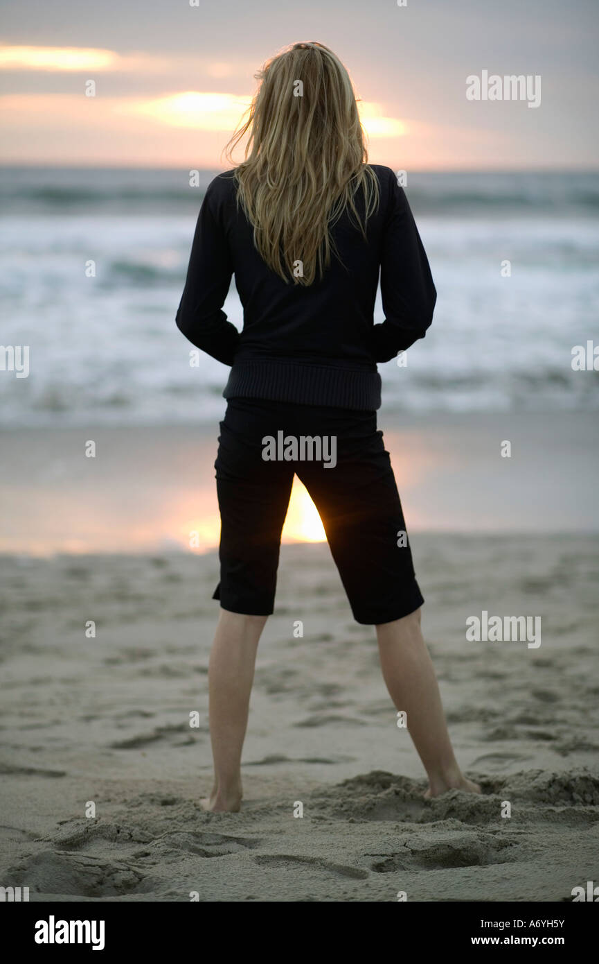 A woman standing on a beach at sunset Stock Photo