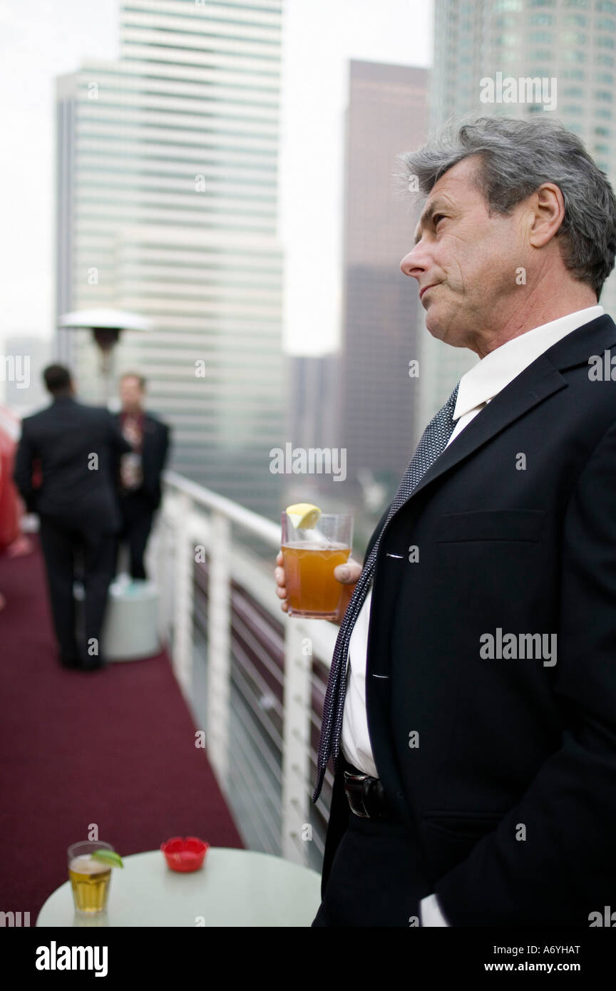 Businessman holding a drink at a roof top bar Stock Photo