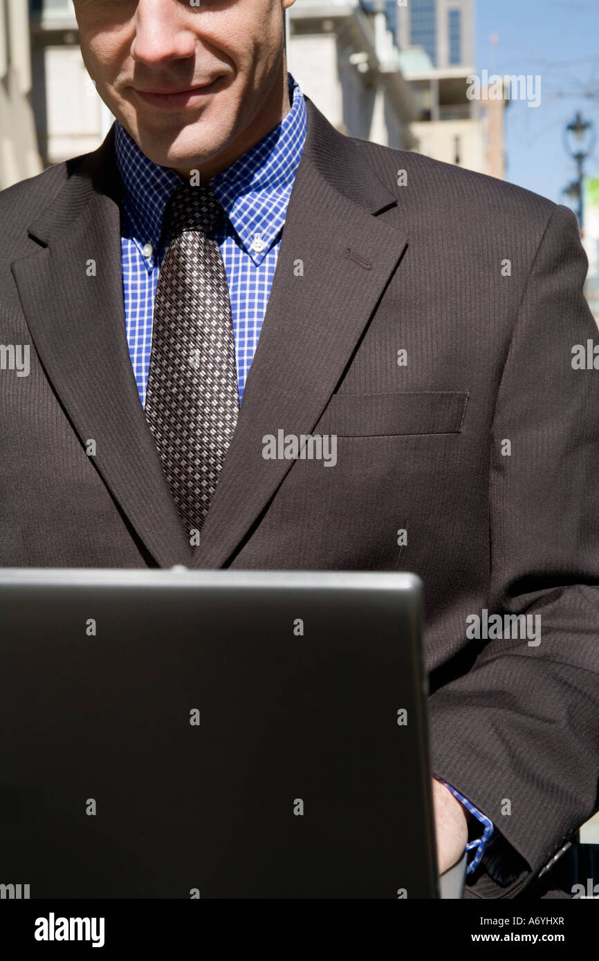Businessman sitting on an outside bench using a laptop Stock Photo - Alamy